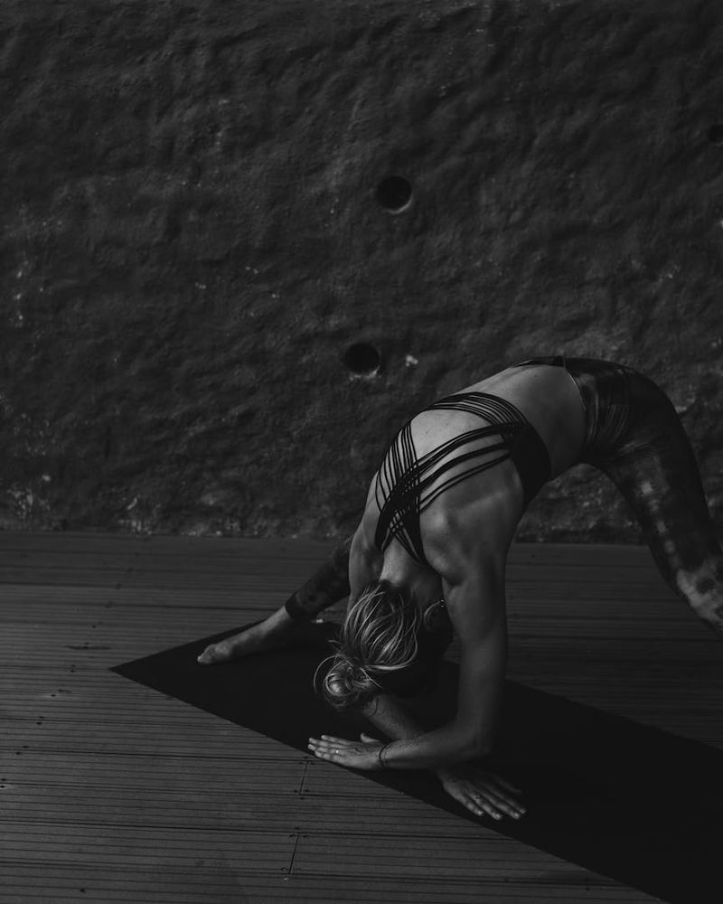 Graceful woman in yoga pose representing balance and core strength in dark studio